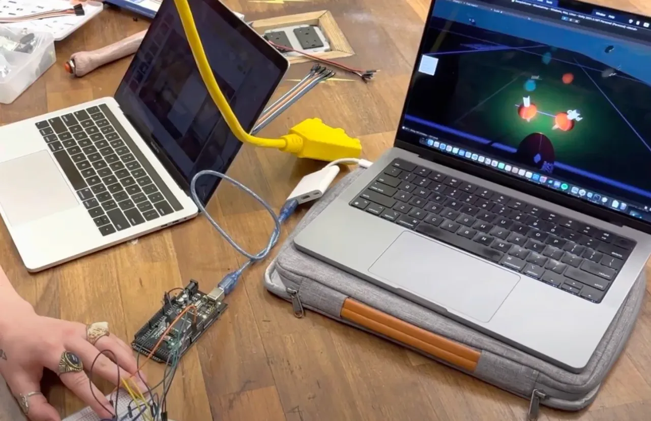 Laptop running the Unity game next to an Arduino prototype wired to a breadboard